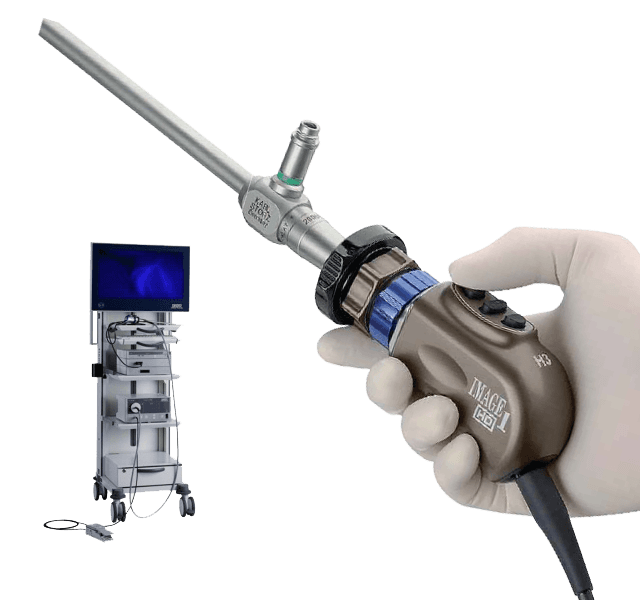 A surgeon's gloved hand holding an HD endoscopic camera, with a surgical monitor tower in the background.