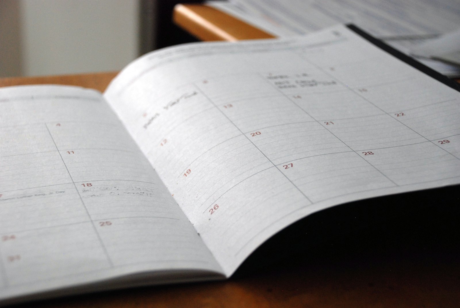 An open monthly planner and pen on a wooden desk, marking a recovery timeline.